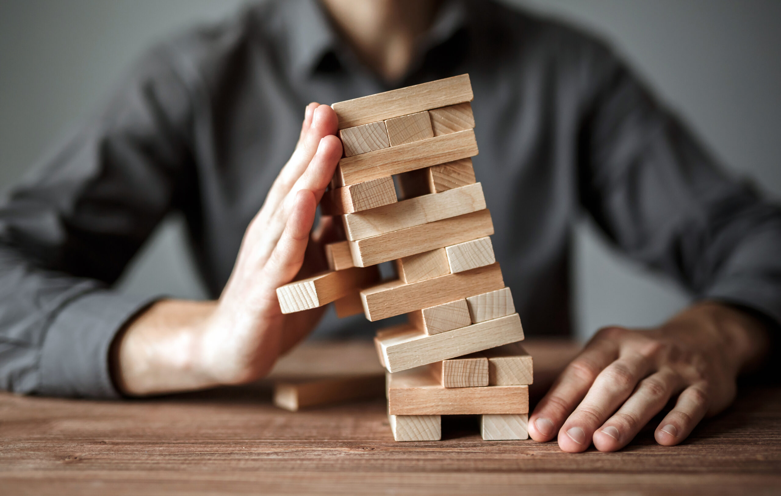 Jenga block tower leaning over showing what can happen from one block missing